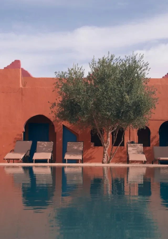 A terracotta-walled courtyard pool with loungers and an olive tree