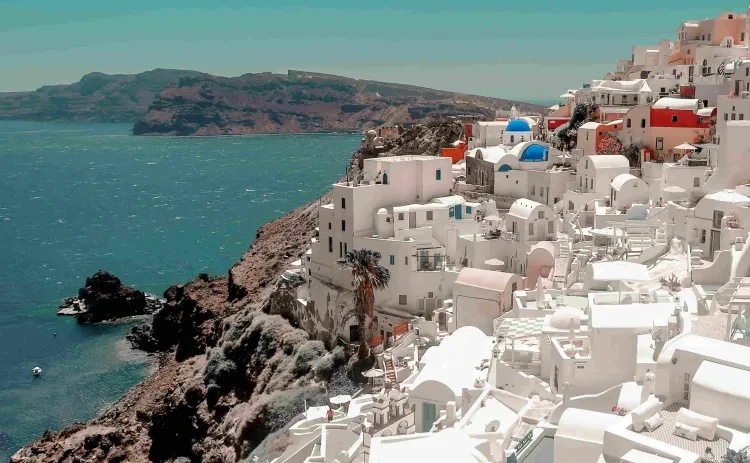 White clifftop houses and blue domes above the sea