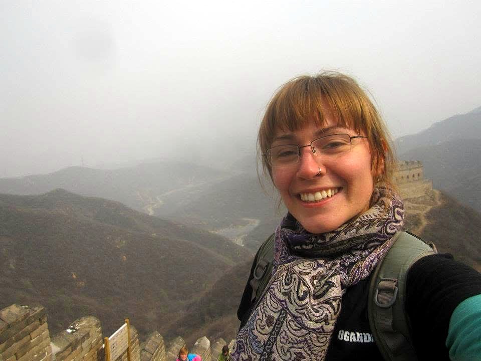 Emily smiling on the Great Wall with misty mountains behind her